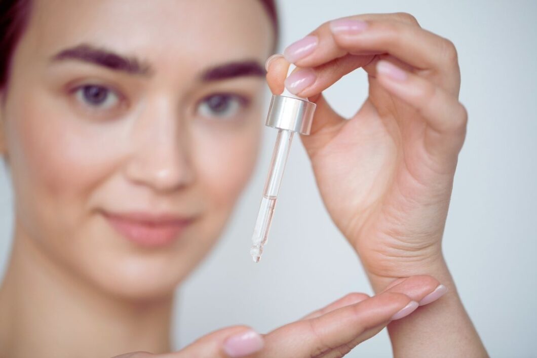 Kobieta trzyma w dłoni pipetę z kwasem salicylowym na twarz