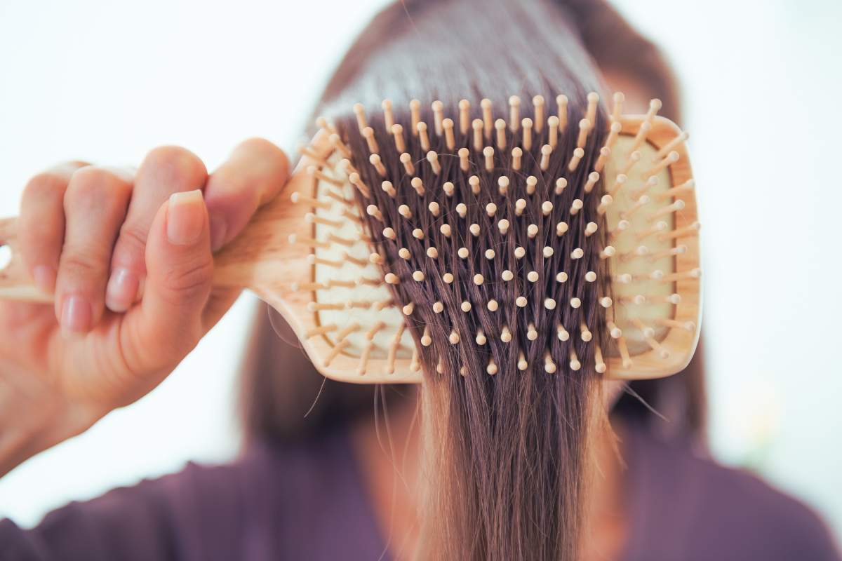 Kobieta czesze włosy szczotką typu paddle brush