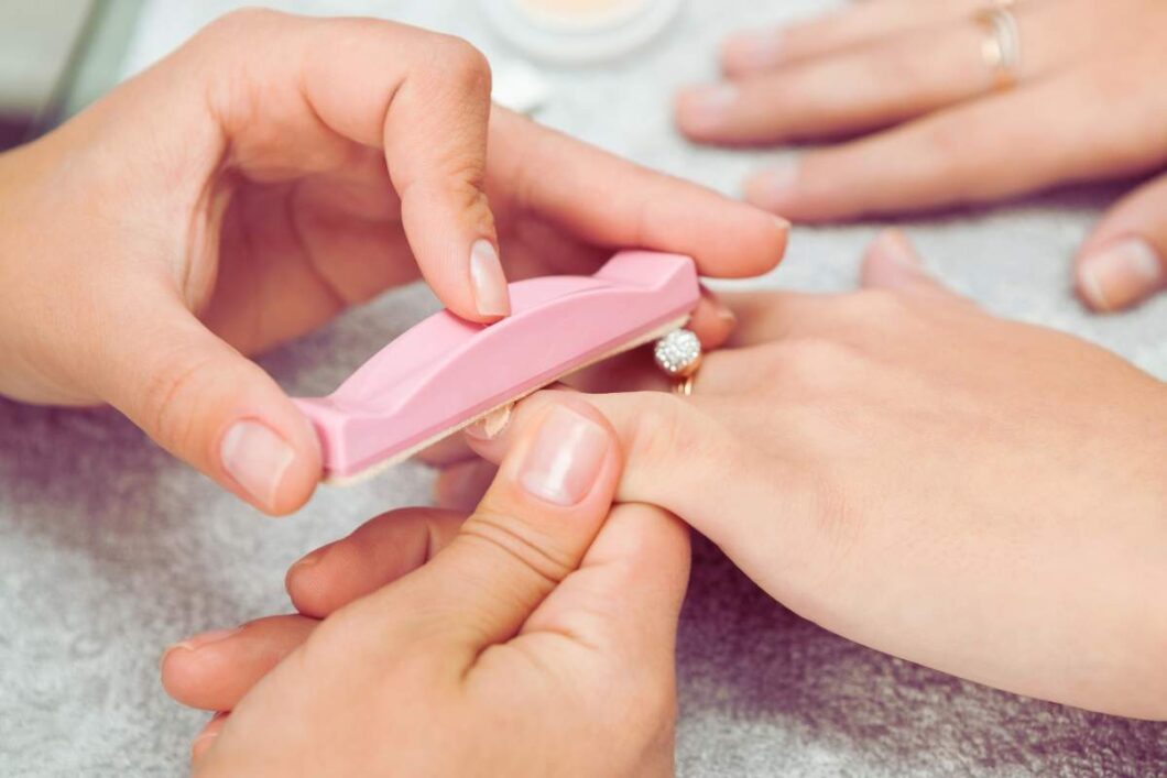 Kobieta pielęgnuje naturalną płytkę paznokciową po zdjęciu manicure hybrydowego