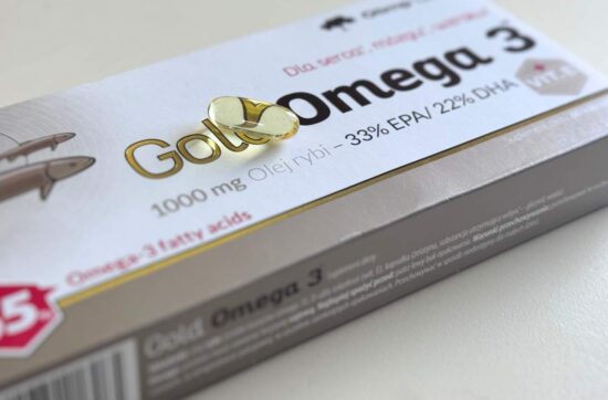 Kapsułka z omega-3 leży na opakowaniu suplementu diety Olimp Gold Omega-3