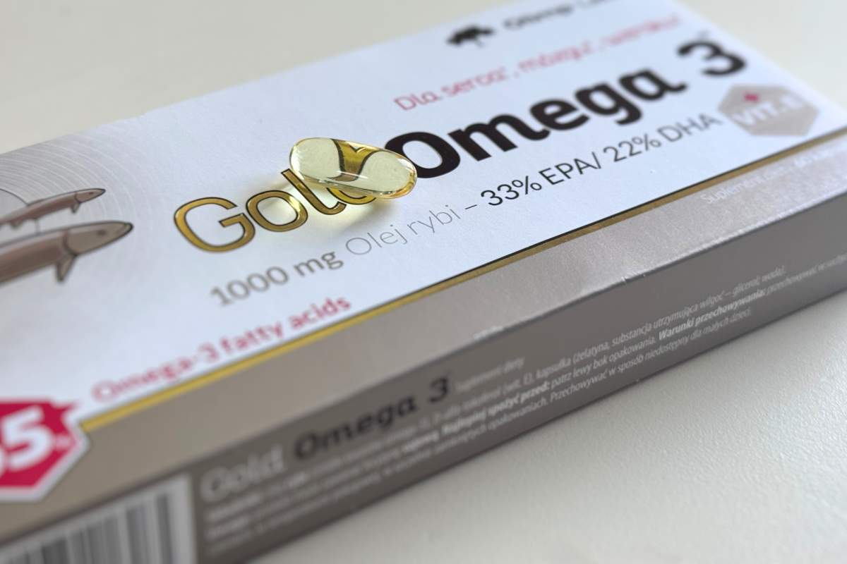 Kapsułka z omega-3 leży na opakowaniu suplementu diety Olimp Gold Omega-3