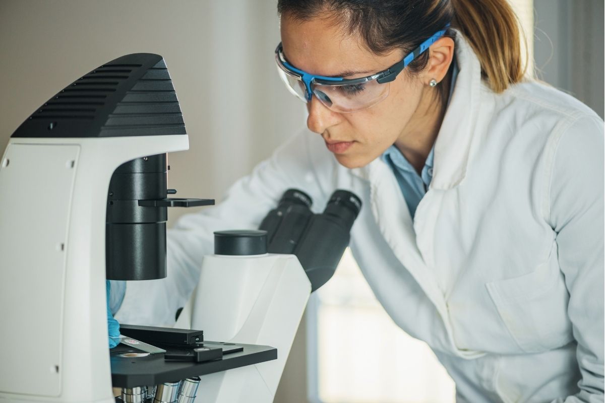 kobieta wykonuje badanie pod mikroskopem