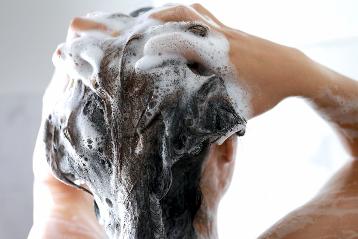 Kobieta myje włosy szamponem na łojotokowe zapalenie skóry