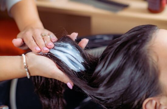 Fryzjerka aplikuje odżywkę na włosy klientki