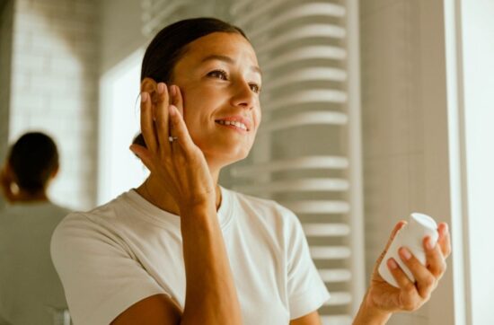 Fotografia przedstawia kobietę, która aplikuje krem do twarzy